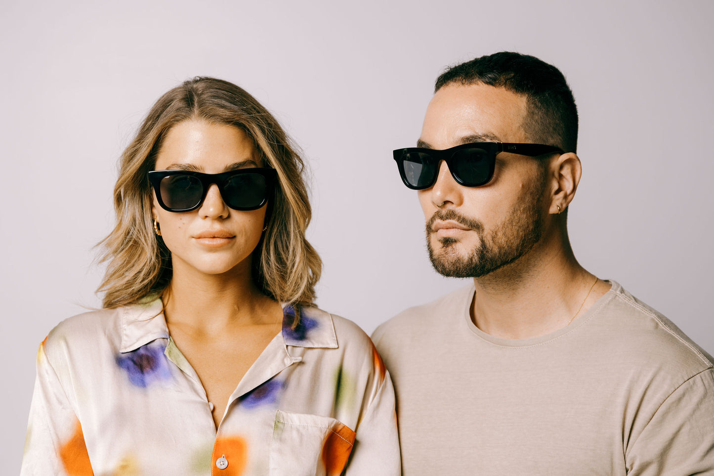 Woman and man both wear black Ike Charcoal classic biodegradable and sustainable sunglasses with dark grey lens