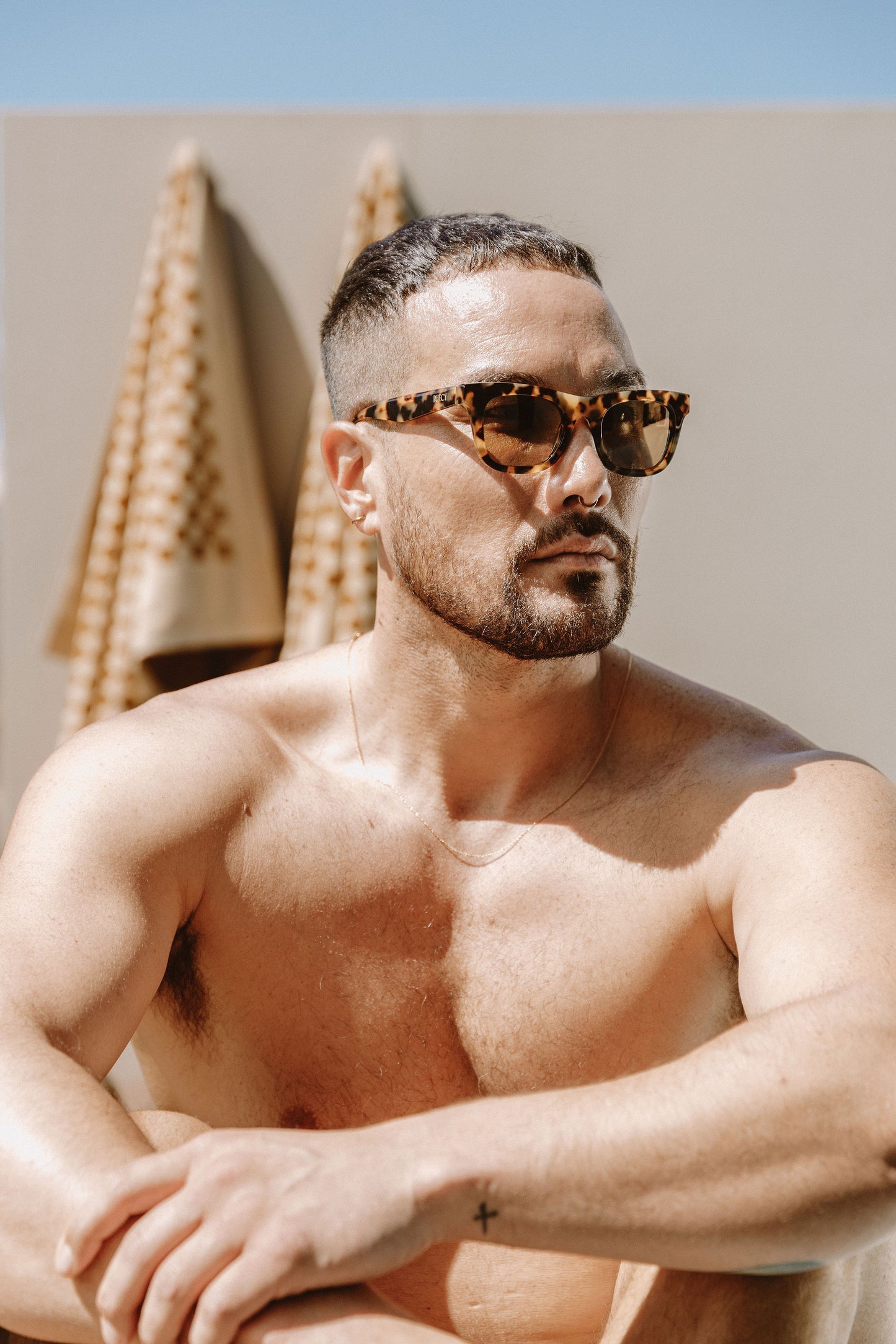 Man without shirt wears brown tortoiseshell biodegradable and sustainable sunglasses with tan lens